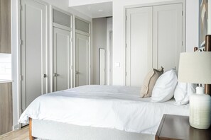 Ein Schlafzimmer mit einem Bett, weißen Wänden und einem Kleiderschrank.