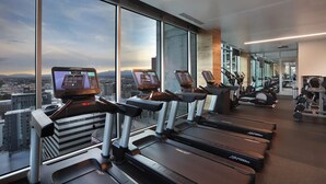 Una palestra moderna con tapis roulant, cyclette e pesi, caratterizzata da ampie vetrate e vista sulla città.