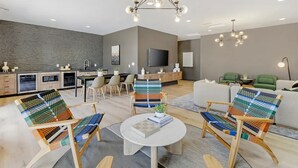 Ein modernes Wohnzimmer mit Essbereich, einer Küche und einem an der Wand befestigten Fernseher.