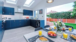Eine moderne Küche mit blauen Schränken, einem eingebauten Backofen und einem großen Fenster mit Blick auf einen Garten.