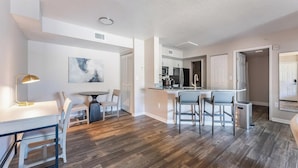 Una cocina moderna con una isla central, un comedor con mesa y sillas, y una zona de bar con taburetes.