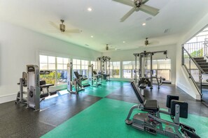 A spacious gym with various exercise machines, large windows, and a staircase. - Landing | Beautiful 1BD, Clubhouse, Game Room (Buckhead)