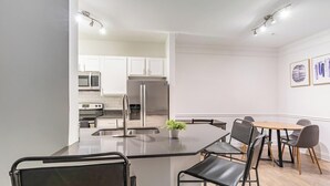 Una cocina moderna con armarios blancos, electrodomésticos de acero inoxidable y una isla central con asientos.