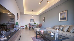 Een moderne woonkamer met een glazen salontafel, een bank en een eethoek met stoelen.