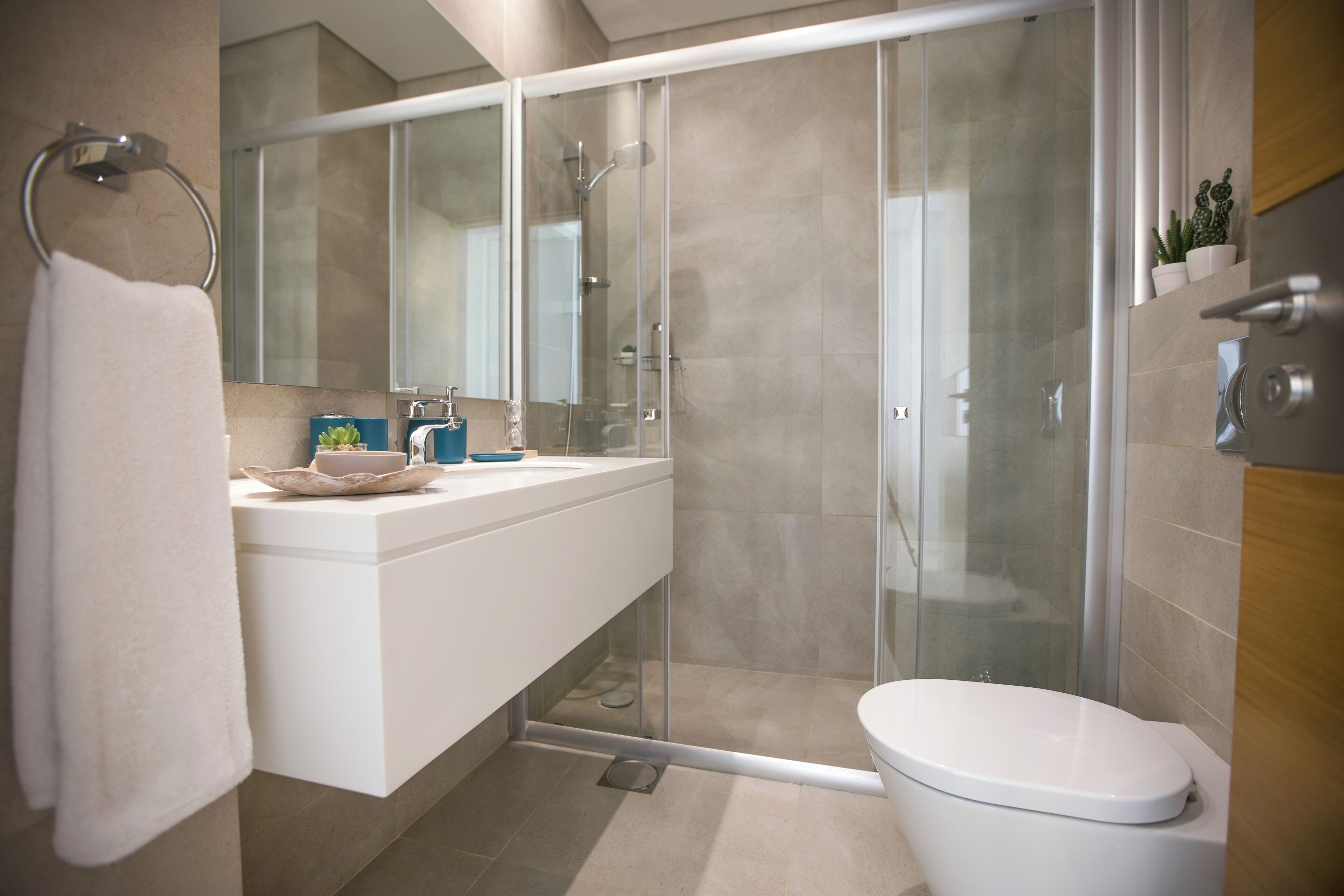 Un baño moderno con ducha de vidrio, lavamanos blanco y retrete.