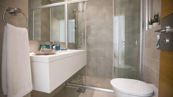 Un baño moderno con ducha de vidrio, lavamanos blanco y retrete.