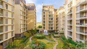 Een modern appartementencomplex met meerdere hoge gebouwen, een centrale binnentuin met groen en een heldere lucht.