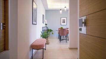 A hallway with a bench, a dining area with chairs and a table, and framed pictures on the walls.