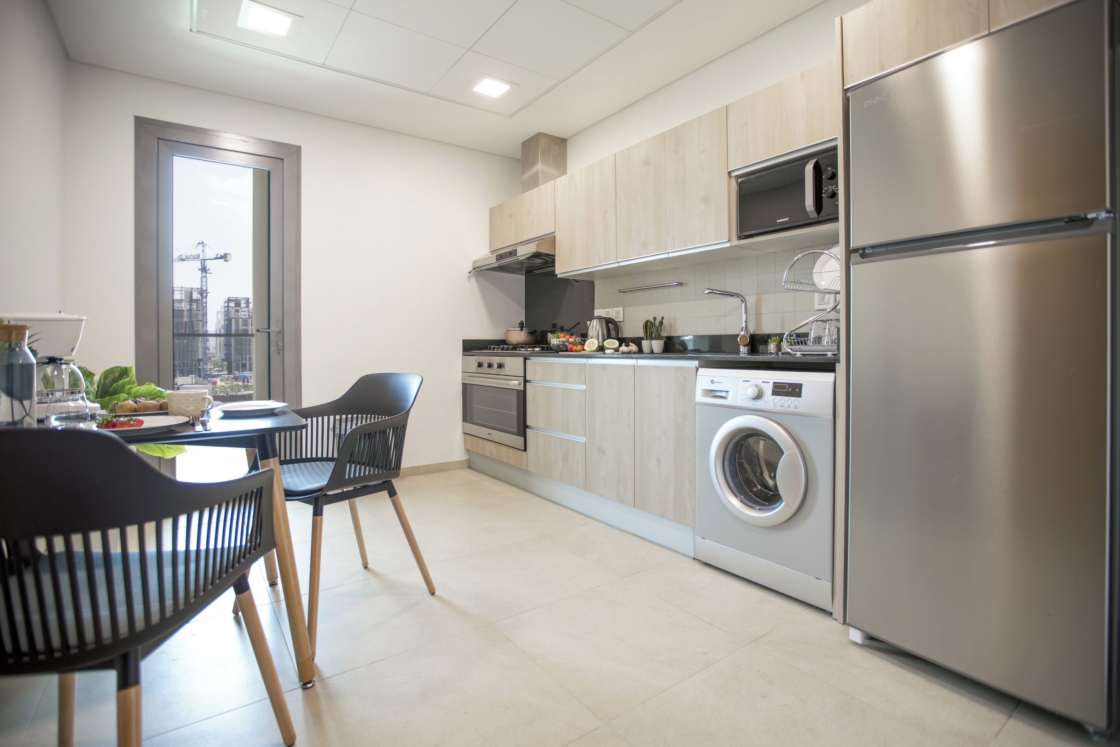 Een moderne keuken met een roestvrijstalen koelkast, een inbouwoven en een wasmachine.