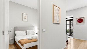 Una camera d'albergo moderna con un letto, una testiera in legno, un piccolo tappeto e un quadro appeso alla parete.