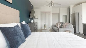 Una habitación de hotel moderna con una cama grande, un escritorio, un sofá y una kitchenette.