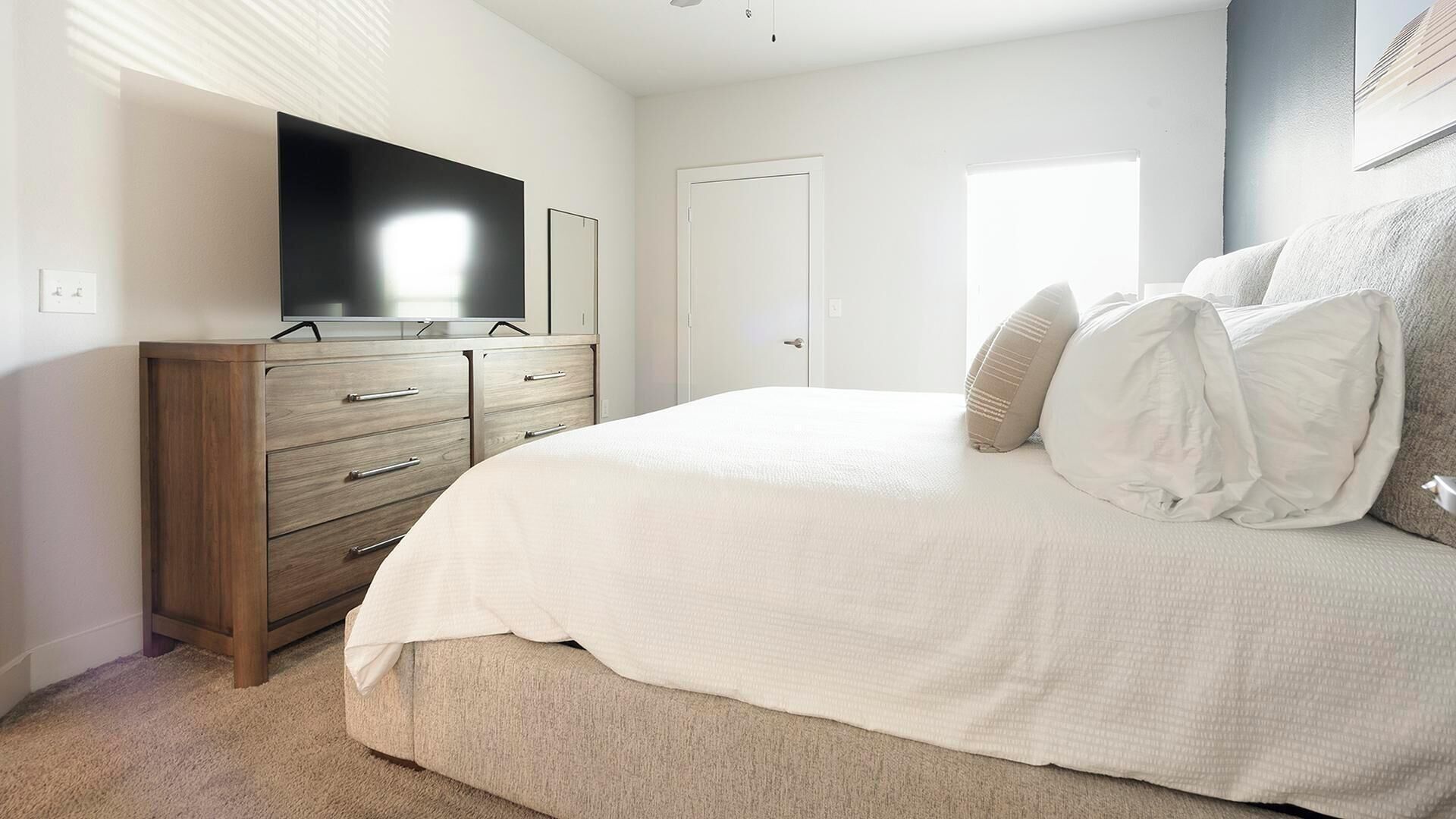 Une chambre à coucher avec un lit, une télévision, une armoire et une porte.