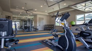 A gym with various exercise equipment, a colorful striped floor, and a large window. - Landing | Incredible Studio, Clubhouse, Gym (San Antonio)