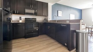 A modern kitchen with dark cabinetry, a built-in oven, microwave, and dishwasher. - Landing | Stunning 1BD, Gym, Tennis Court (Fort Myers)