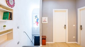 Ein Flur mit einer Treppe, einer Tür mit der Aufschrift "PANARO APARTMENT" und einer an der Wand befestigten Uhr.