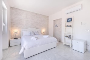 A modern bedroom with a large bed, bedside tables, a wardrobe, and a small white cabinet. - RELAIS ROMA BEACH (Fiumicino)