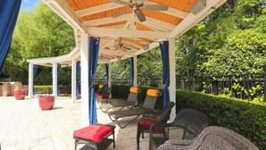 Eine Terrassenanlage im Freien mit überdachter Sitzgruppe, darunter Liegestühle und ein kleiner Tisch.