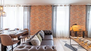 Uma sala de estar moderna com parede de tijolos, sofá de couro, mesa de jantar com cadeiras e uma mesa de centro.