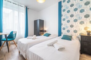 A hotel room with two beds, a desk, and a chair. There is a wardrobe and a wall with a geometric pattern. - T4 INDUSTRIAL STYLE NEAR THE HISTORIC DOWNTOWN   (Vannes)