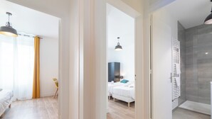 Quarto de hotel com cama, mesa de cabeceira, abajur e área de chuveiro.