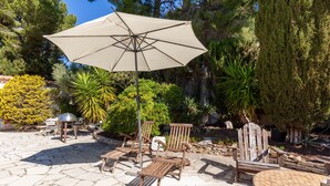 An outdoor patio with stone flooring, wooden chairs, a round table, and a large umbrella. - Holiday Home 'Petite Maison' with Shared Pool, Communal Terrace and Wi-Fi (Carry-le-Rouet)