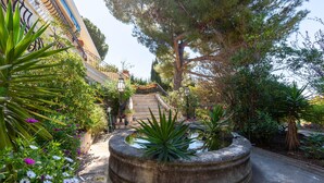 A garden with a circular planter, a staircase, and a building with balconies. - Holiday Home 'Petite Maison' with Shared Pool, Communal Terrace and Wi-Fi (Carry-le-Rouet)