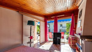 A bedroom with a bed, a TV, a lamp, and a view of the outside. - Holiday Home 'Petite Maison' with Shared Pool, Communal Terrace and Wi-Fi (Carry-le-Rouet)