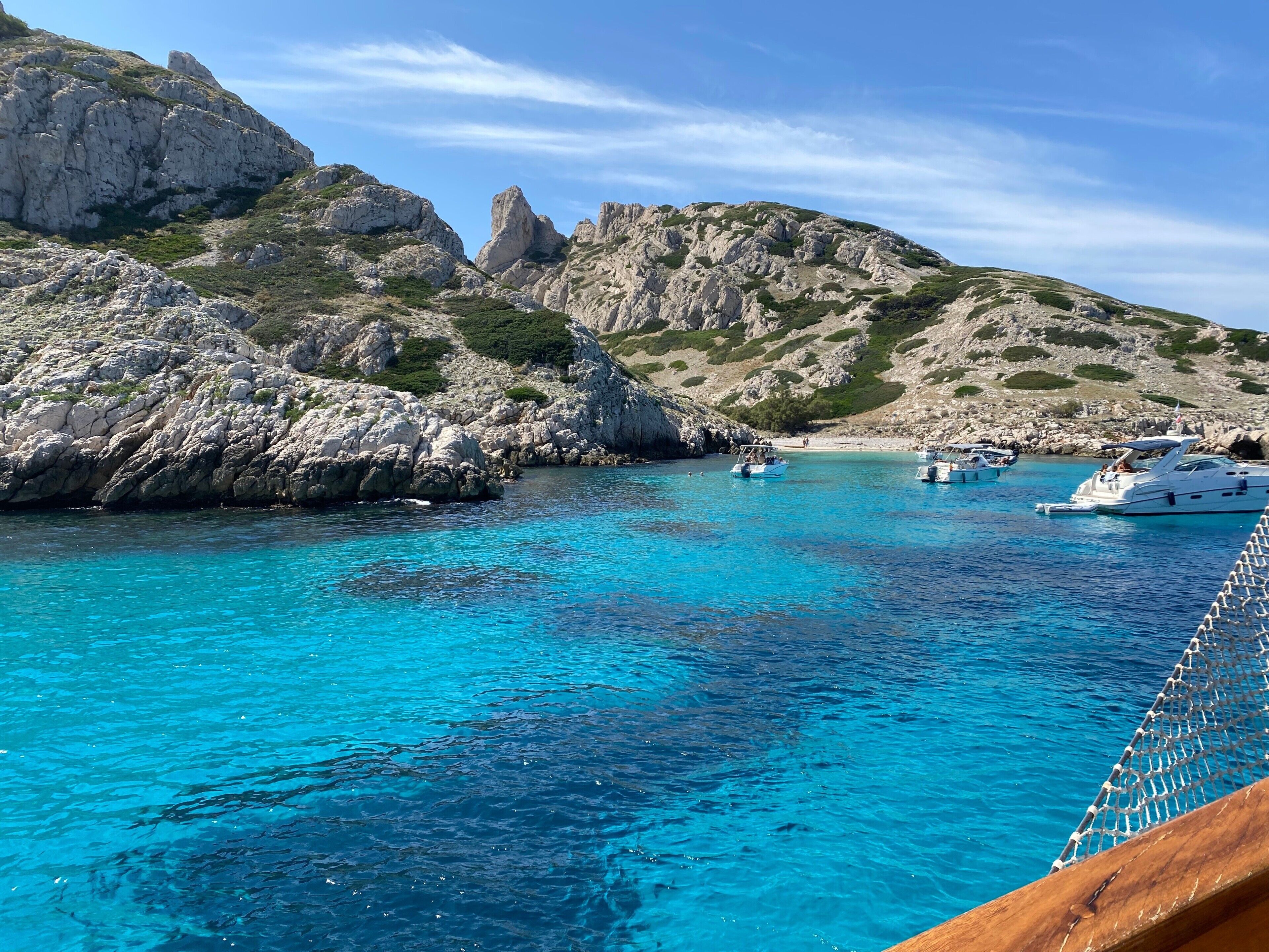 Eine Küstenlandschaft mit klarem türkisblauem Wasser, felsigen Klippen und Booten.