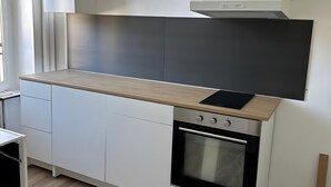 A modern kitchen with white cabinetry, a wooden countertop, and a built-in oven. - Studio Apartment for 2 with Mountain View (La Bourboule)