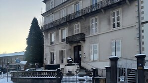 A multi-story building with a gated entrance, a staircase leading to the entrance, and a snow-covered ground. - Studio Apartment for 2 with Mountain View (La Bourboule)