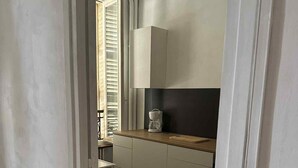 A kitchen with white cabinets, a wooden countertop, and a window with blinds. - Studio Apartment for 2 with Mountain View (La Bourboule)