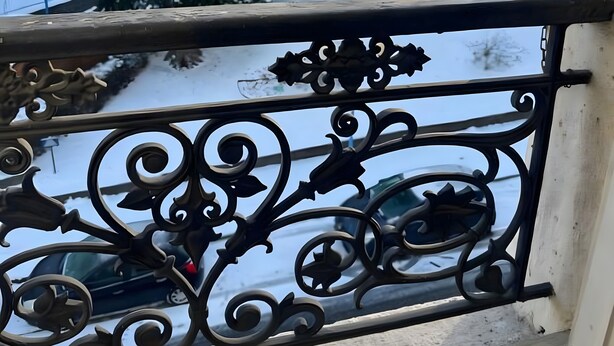 A balcony with ornate metal railings overlooking a snowy landscape with trees and buildings. - Studio Apartment for 2 with Mountain View (La Bourboule)