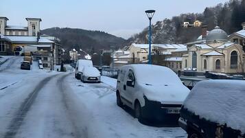 Een besneeuwde straat met geparkeerde auto's en gebouwen op de achtergrond.