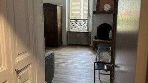 A hallway with a radiator, a window with shutters, and a door. - Studio Apartment for 2 with Mountain View (La Bourboule)