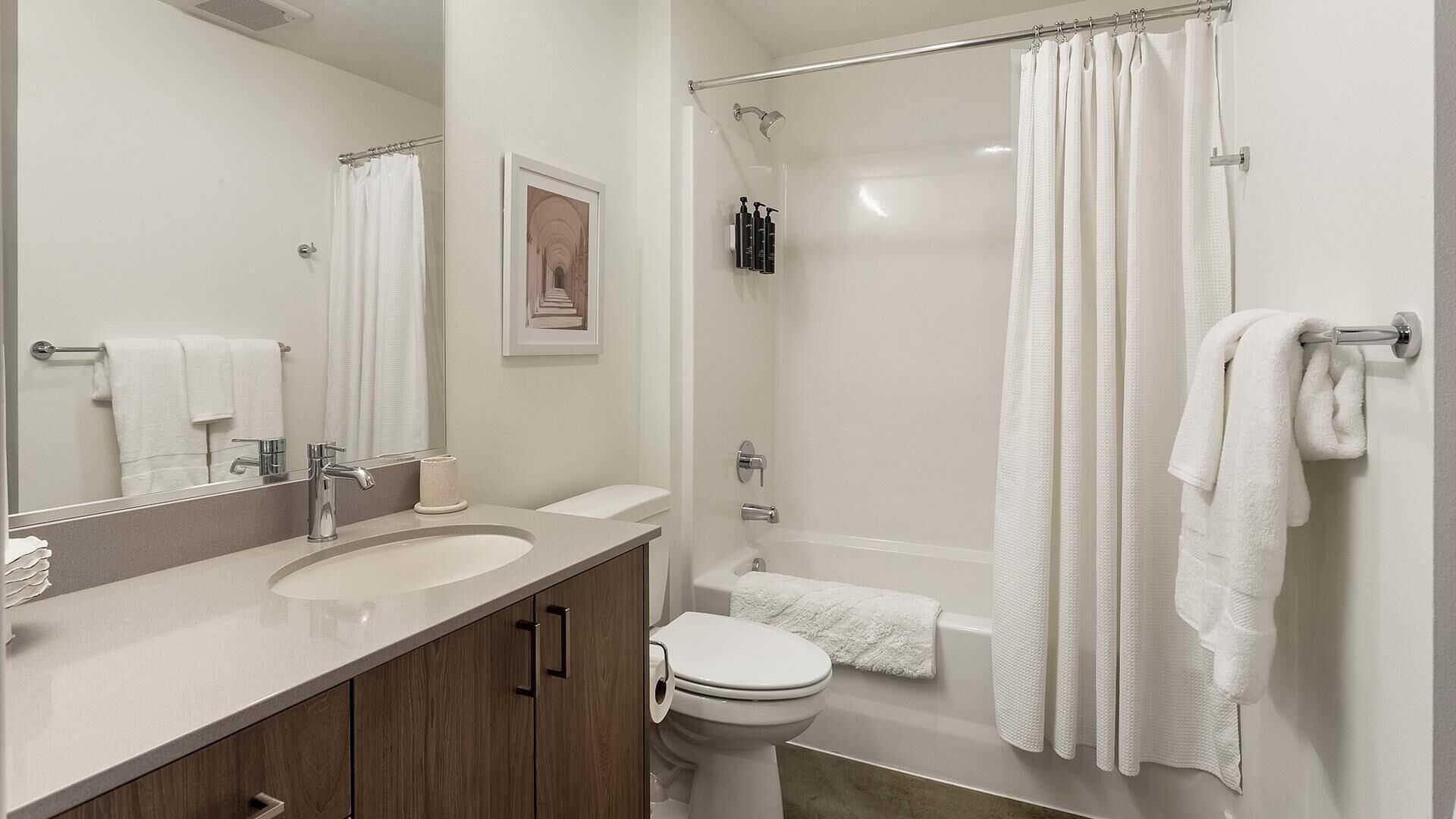 A modern bathroom with a sink, mirror, toilet, and shower.