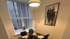 A dining area with a table set for four, a hanging lamp, a framed picture on the wall, and a window with blinds. - Stunning 2 Bed 2 Bath City Centre Apartment Liverpool (Liverpool)