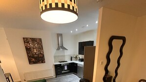 A modern living room with green sofas, a marble coffee table, and a kitchen in the background. - Stunning 2 Bed 2 Bath City Centre Apartment Liverpool (Liverpool)