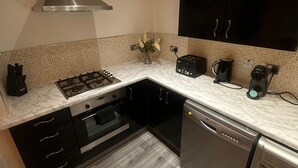 A modern kitchen with a gas stove, oven, dishwasher, and black cabinets. - Stunning 2 Bed 2 Bath City Centre Apartment Liverpool (Liverpool)