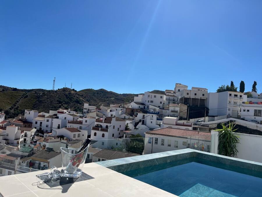 A rooftop pool with a clear view of a white-washed town and a hill in the background.