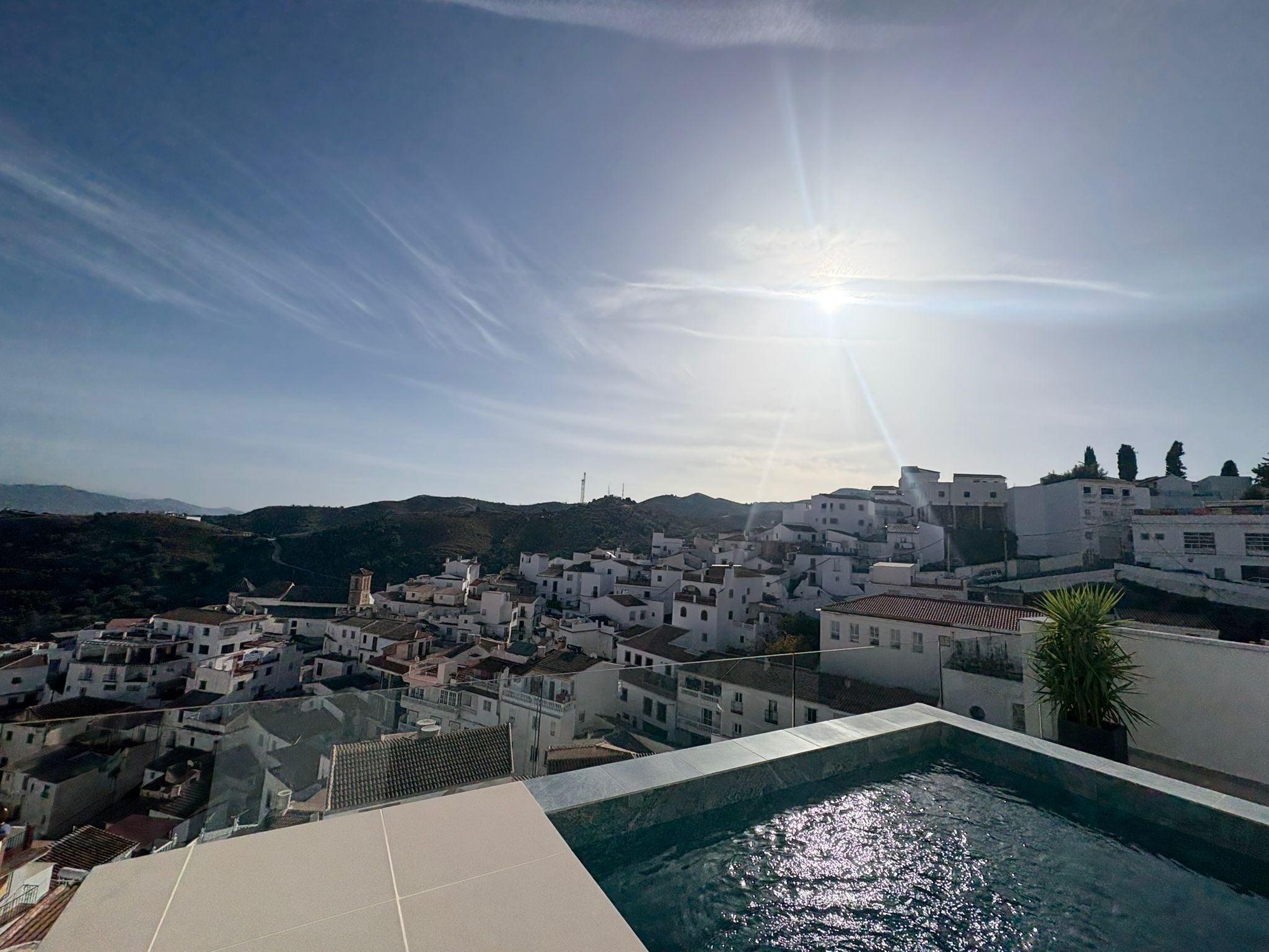 Vue sur une ville côtière depuis la piscine, avec ses bâtiments blancs et son ciel dégagé.