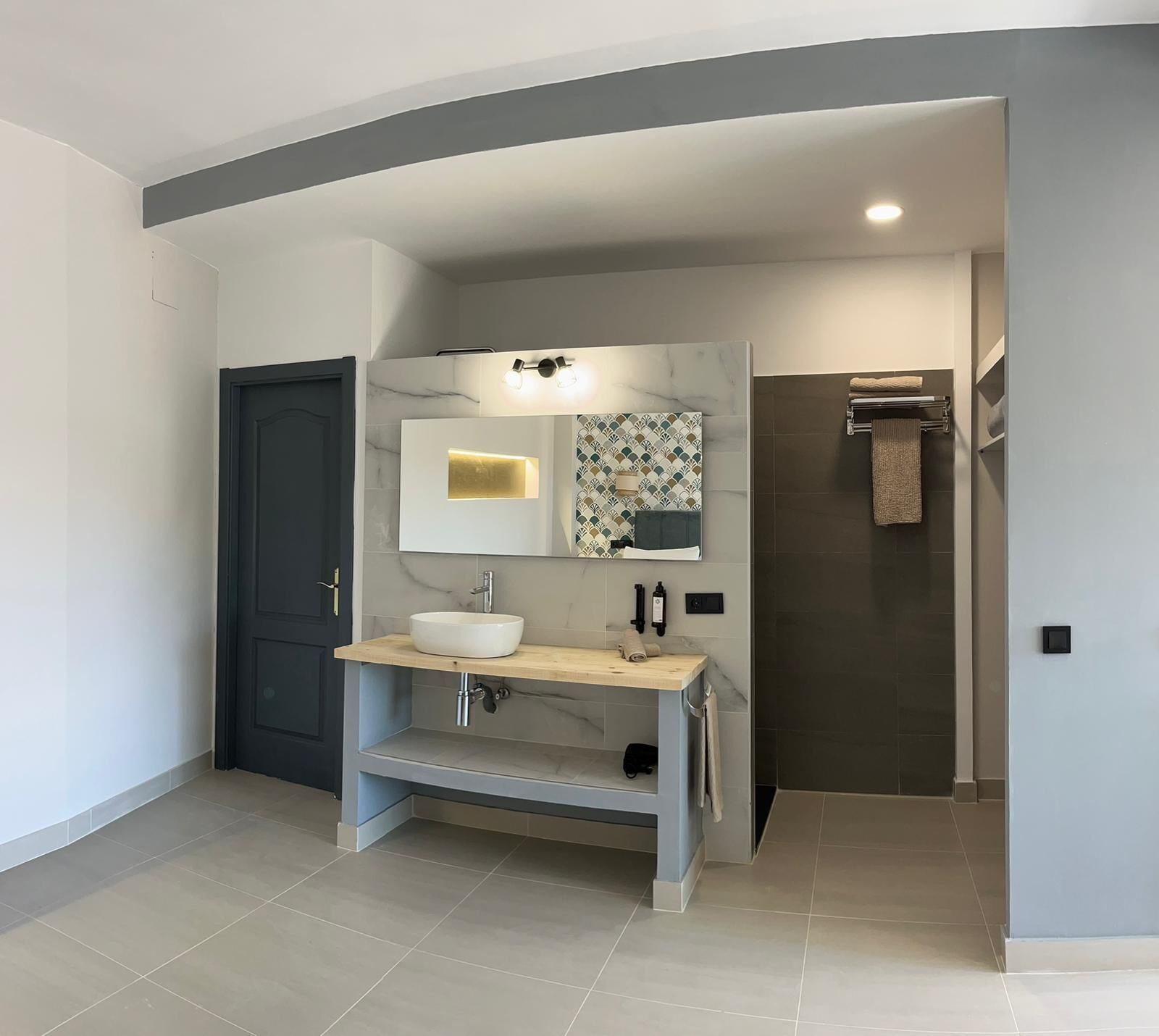 Une salle de bain moderne avec un meuble-lavabo en marbre, un grand miroir et un porte-serviettes.