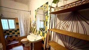 Casa de banho com chão xadrez, sanita, lavatório e espelho com moldura decorativa.
