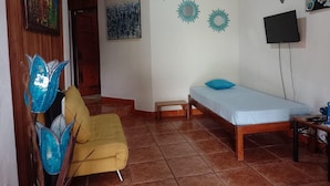 Habitació amb llit, sofà, televisió i decoració mural.