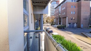 A view from a balcony overlooking a street with parked cars, a building with a brick facade, and a clear sky. - Seabreeze Suites (Southampton)