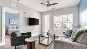 Ein modernes Wohnzimmer mit Flachbildfernseher, Deckenventilator und Sofa.