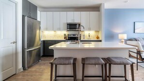 Una cocina moderna con una isla central, electrodomésticos de acero inoxidable y una zona con taburetes de bar.