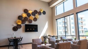 Una sala de estar moderna con televisor de pantalla plana, comedor y ventanas amplias que ofrecen vistas del paisaje urbano.