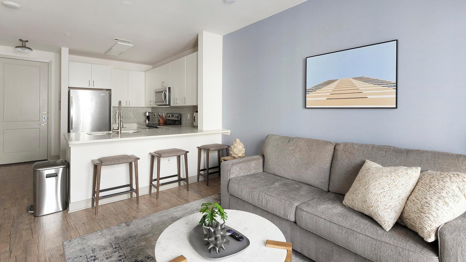 A modern living room with a grey sofa, a coffee table, and a small plant.