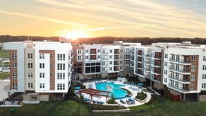 Ein modernes Apartmenthaus mit einem zentral gelegenen Schwimmbad, umgeben von Lounges und Sitzmöglichkeiten im Freien.