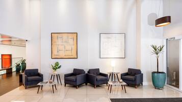 Um lobby moderno com área de estar, duas grandes pinturas abstratas e um vaso de planta.